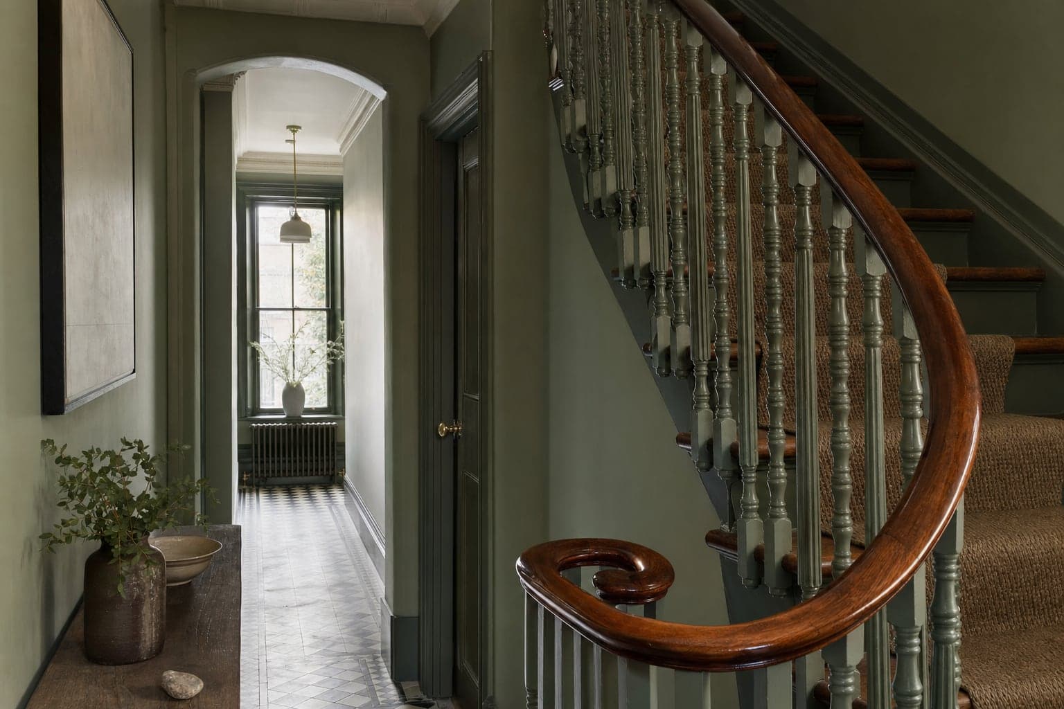 A Victorian hallway with a curved mahogany handrail glowing with a deep polished finish